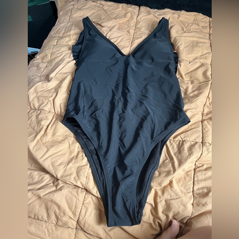 New with tags black open back one peice bathing suit. Size medium